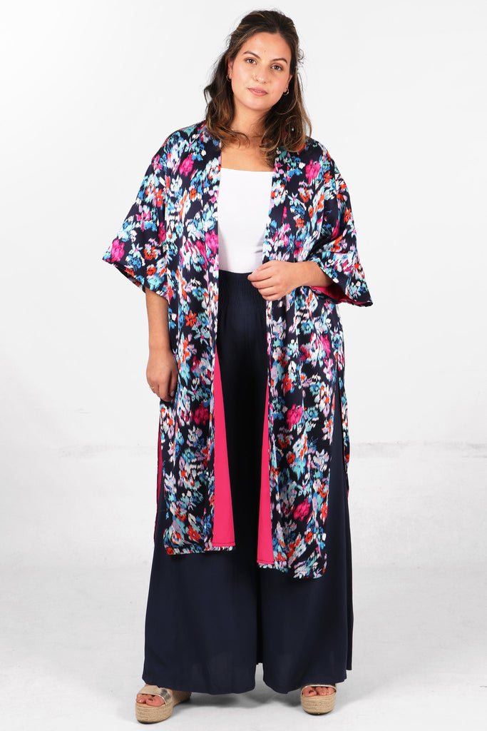 model wearing a mutlicolorued floral print kimono jacket with pink lining, the floral print is navy blue, white, red and pink