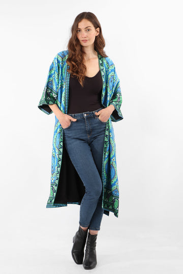 model wearing a midi length open front kimono with 3/4 sleeves, the kimono is turquoise and green with an all over mandala print pattern