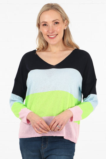 model waring a colour block striped cotton jumper in navy blue,  light blue, lime green and pink,