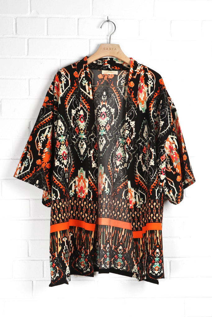 open front short kimono with black and orange mandala patterns draped on a coat hanger