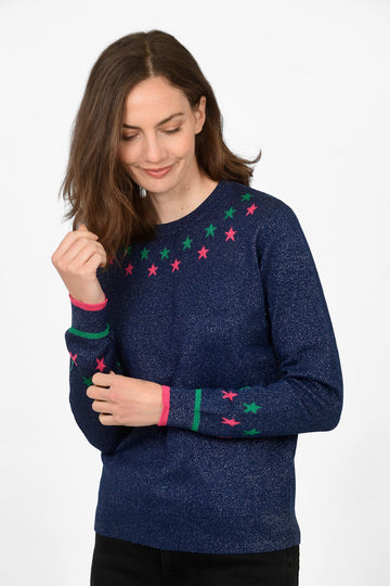 model wearing a navy blue glittery jumper with a green and pink star pattern around the neckline