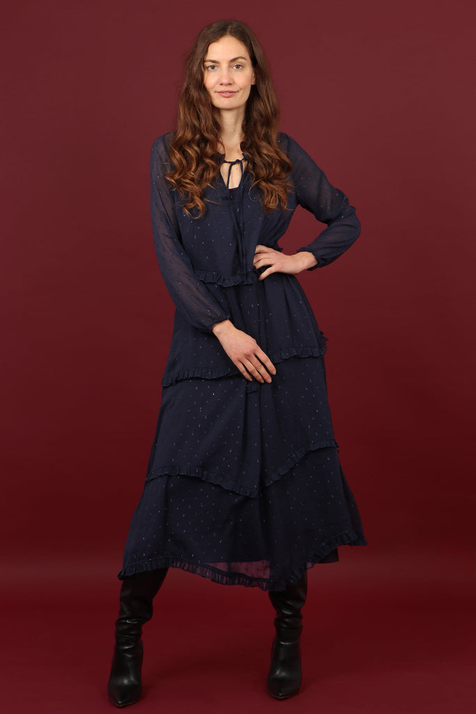 model wearing a navy blue sheer midi tiered dress with an all over dobby pattern, dress has an navy blue under slip