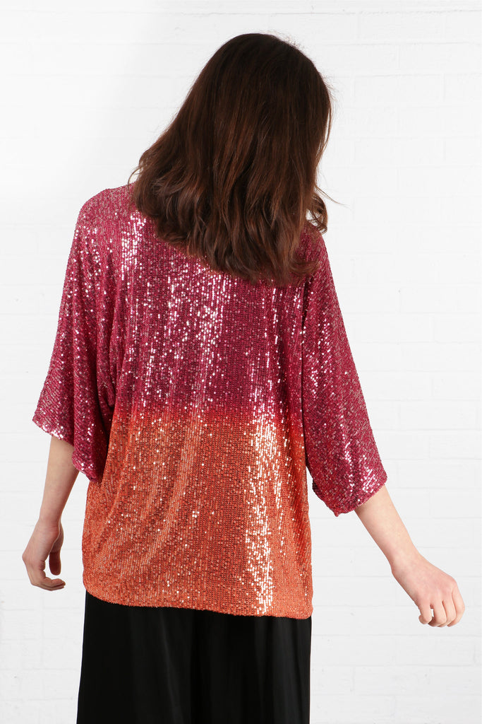 model showing the back of the kimono top which is fully covered in sequin and is pink and orange ombre, pink at the top orange at the bottom
