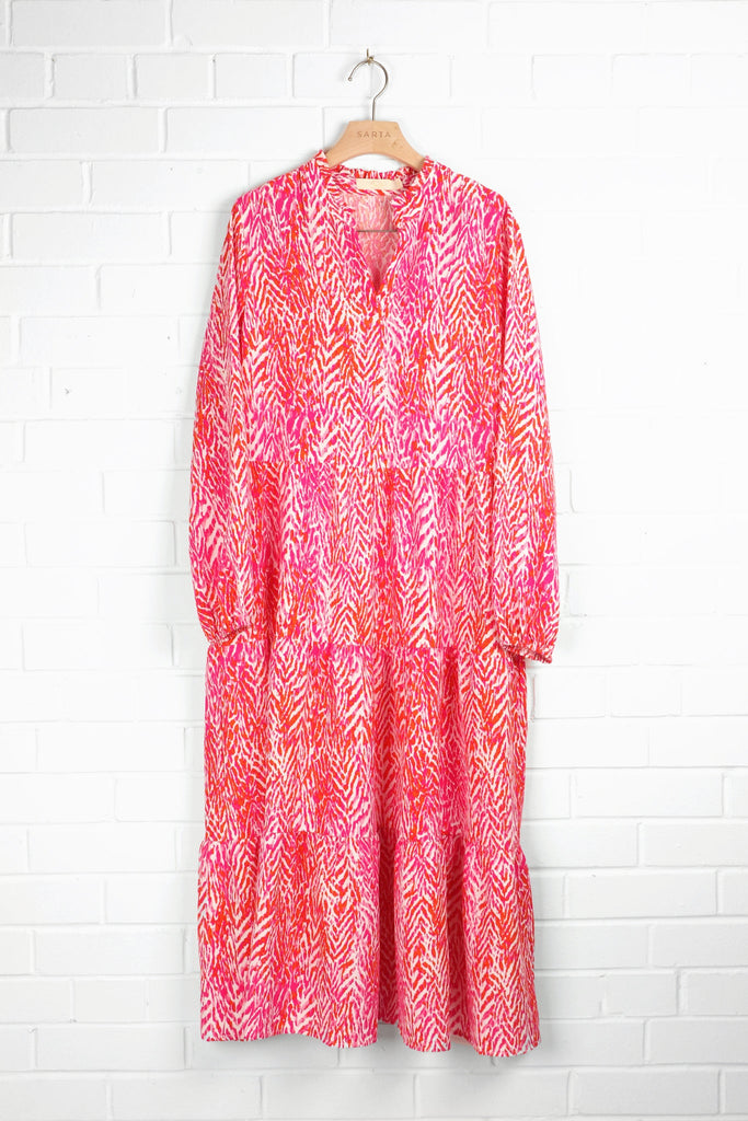pink chevron pattern tiered midi dress with long sleeves draped on a coat hanger
