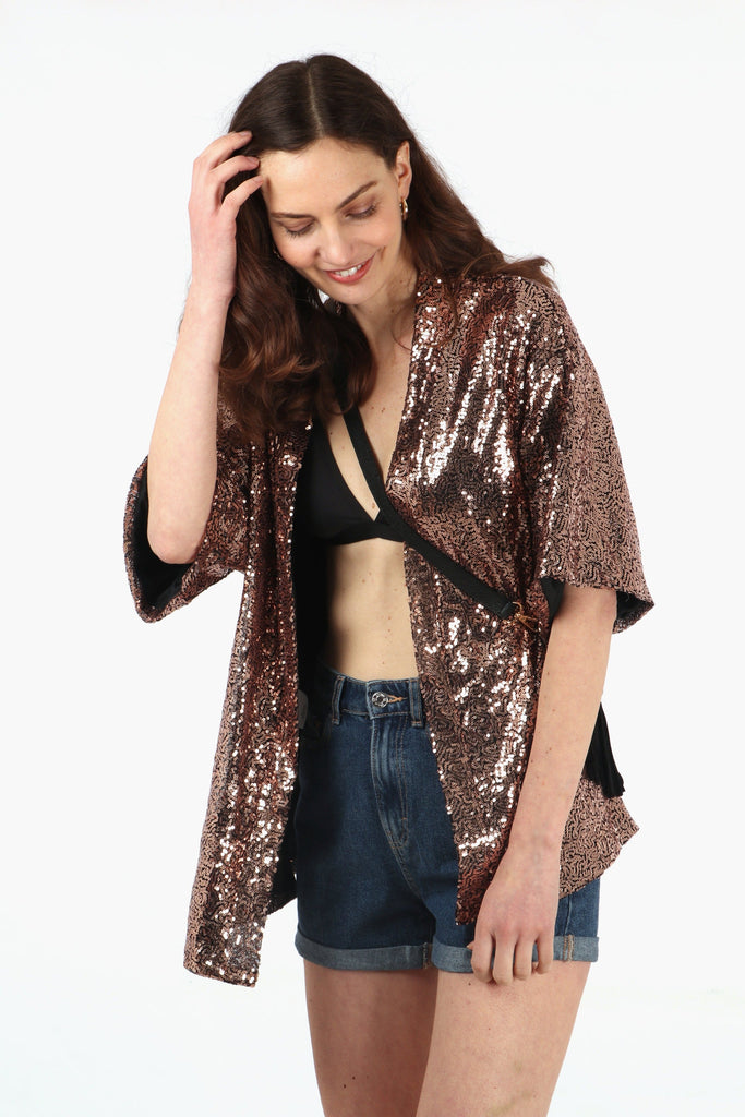 model wearing a bronze sparkly sequin short kimono jacket with an all over sparkly appearance