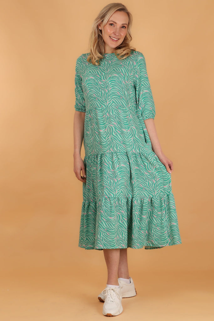 model wearing a green and pink zebra and lightning bolt print midi tiered dress with 3/4 sleeves