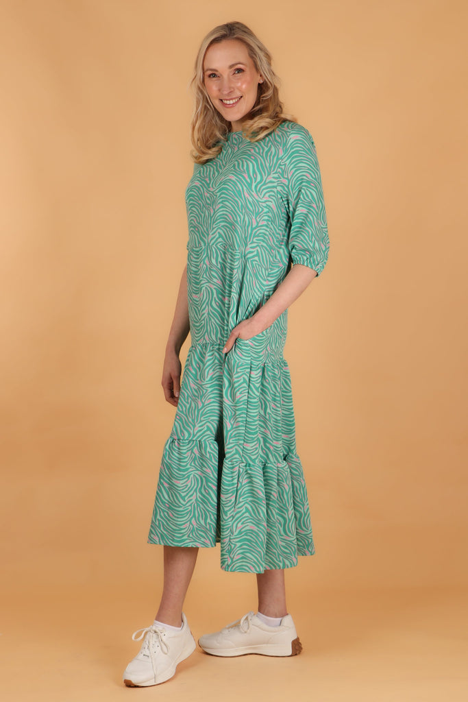 model showing that this loose fitting green and pink midi dress has side pockets