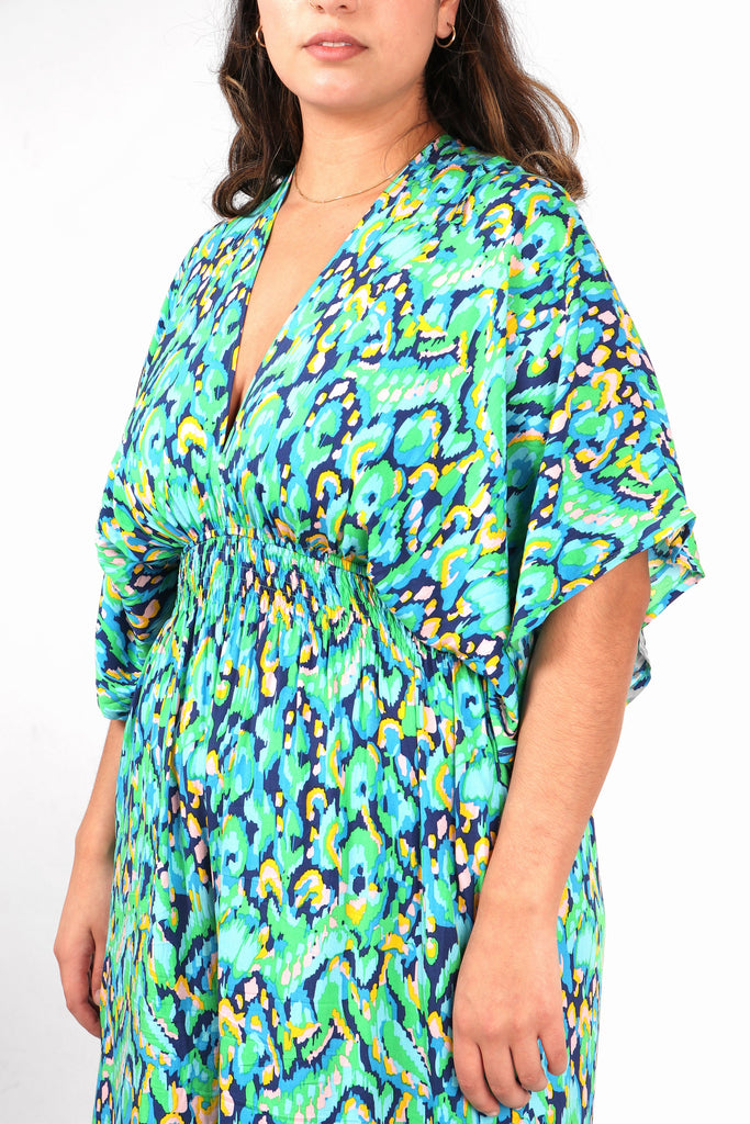 close up of the green abstract print pattern, shirred waist and plunging v neck