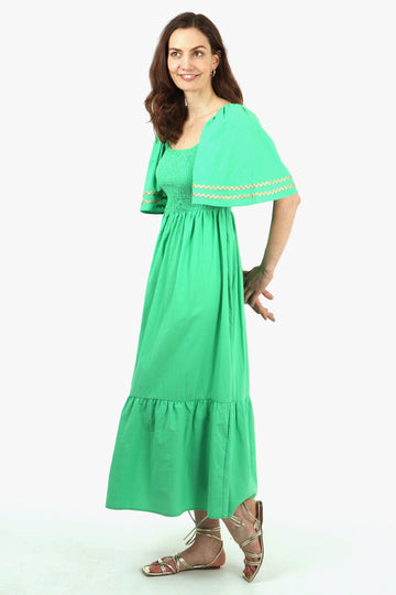 model showing a side view of the maxi cotton milkmaid dress showing the trimmed bell sleeves and fully shirred bust