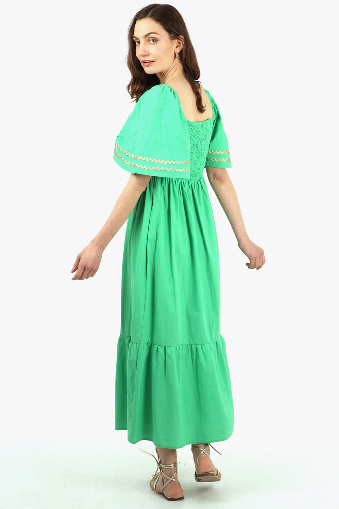 model showing the back of the green milkmaid dress, showing the fully shirred bodice and square neckline