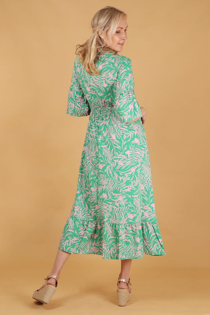 model showing the back of the maxi dress, showing an all over pattern and shirred waist