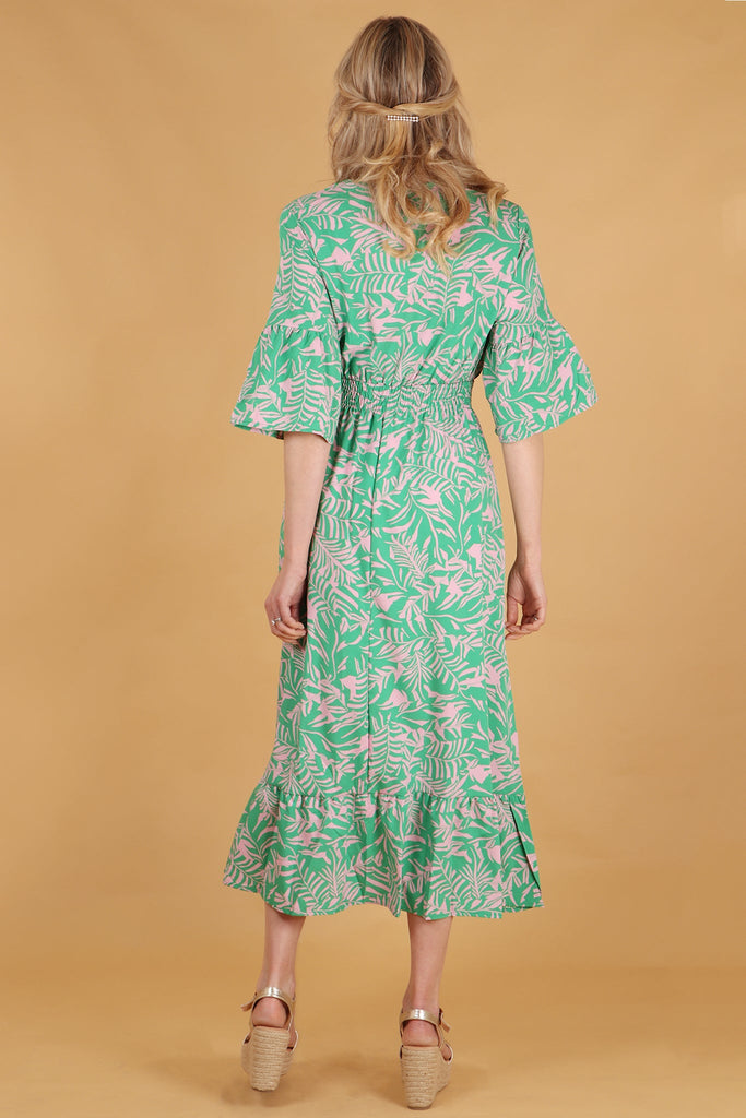 model showing the back of the dress, showing an all over print, shirred waist and 3/4 fluted sleeves