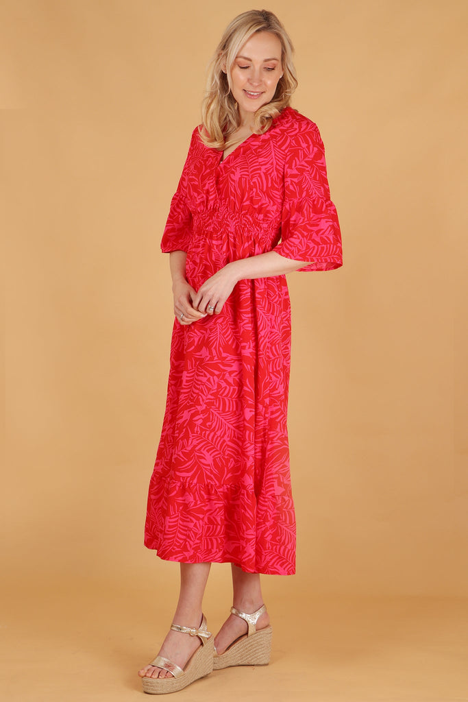 model showing the side view of the dress, showing the loose fitting design, shirred waist and 3/4 sleeves