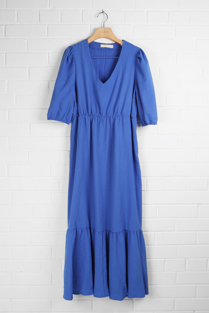blue textured tierd summer dress with vneck and puff sleeves draped on a coat hanger