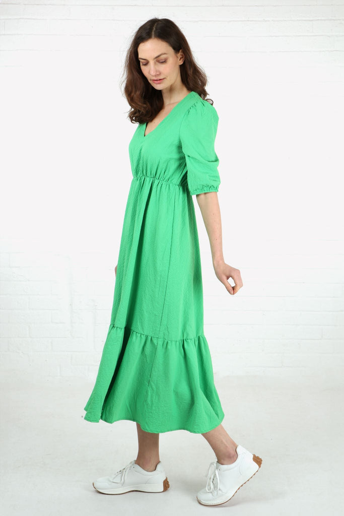 model wearing a midaxi length green v neck tiered dress with elbow length sleeves