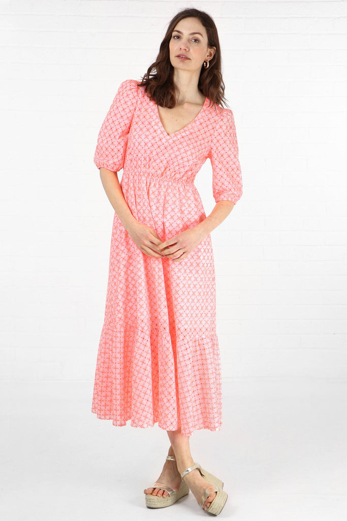 model wearing a tiered midaxi length  v neck dress with a brorderie anglaise pattern