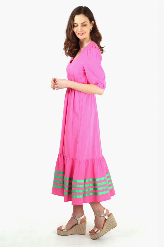 model showing the side view of the pink tiered dress, showing the elbow length sleeves and long maxi length hem