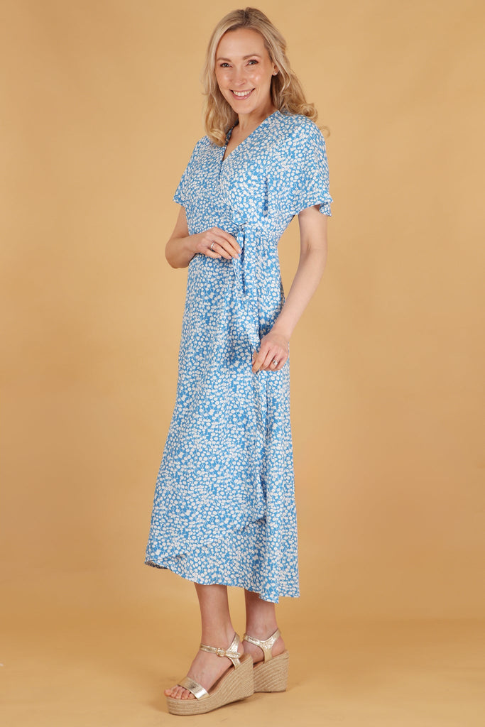 model showing a side view of the dress, showing the dipped hem and waist tie on the wrap dress