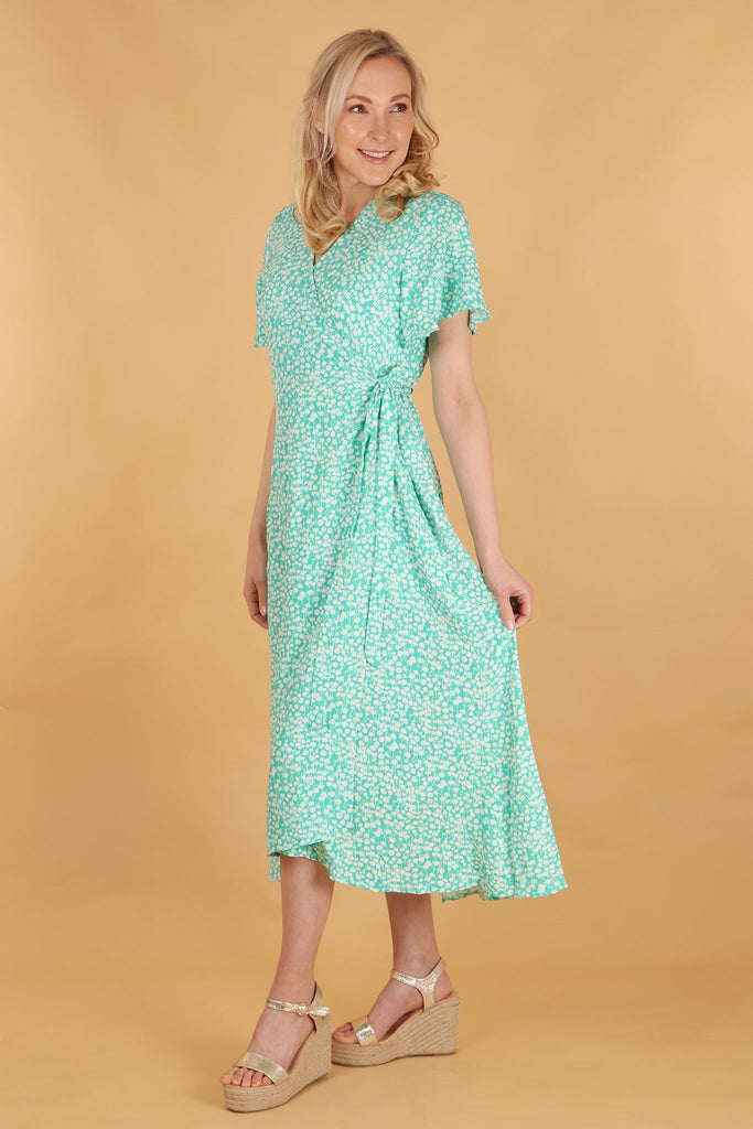 model showing a side view of the dress, showing the dipped hem and waist tie on the wrap dress