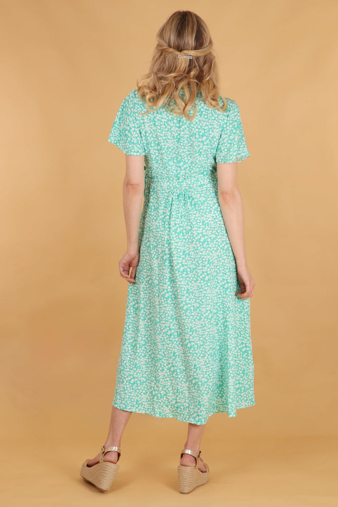 model showing the back of the dress and the all over ditsy floral print pattern