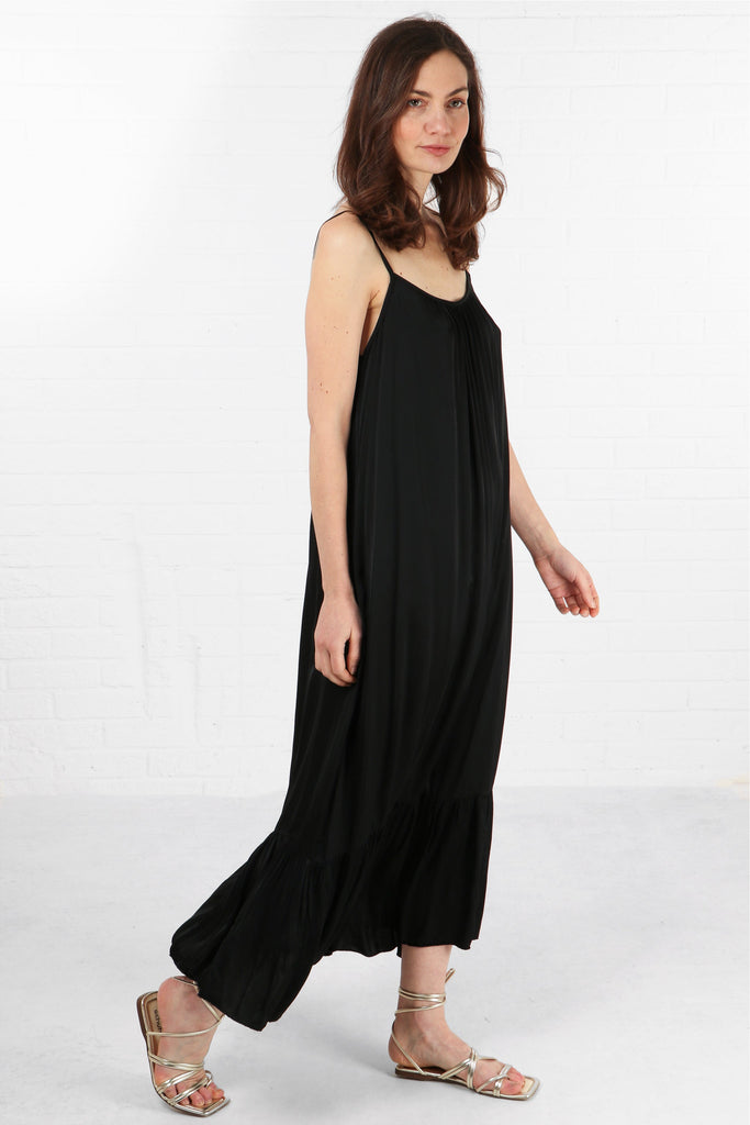 model wearing a loose fitting round neck black tiered maxi dress with thin shoulder straps