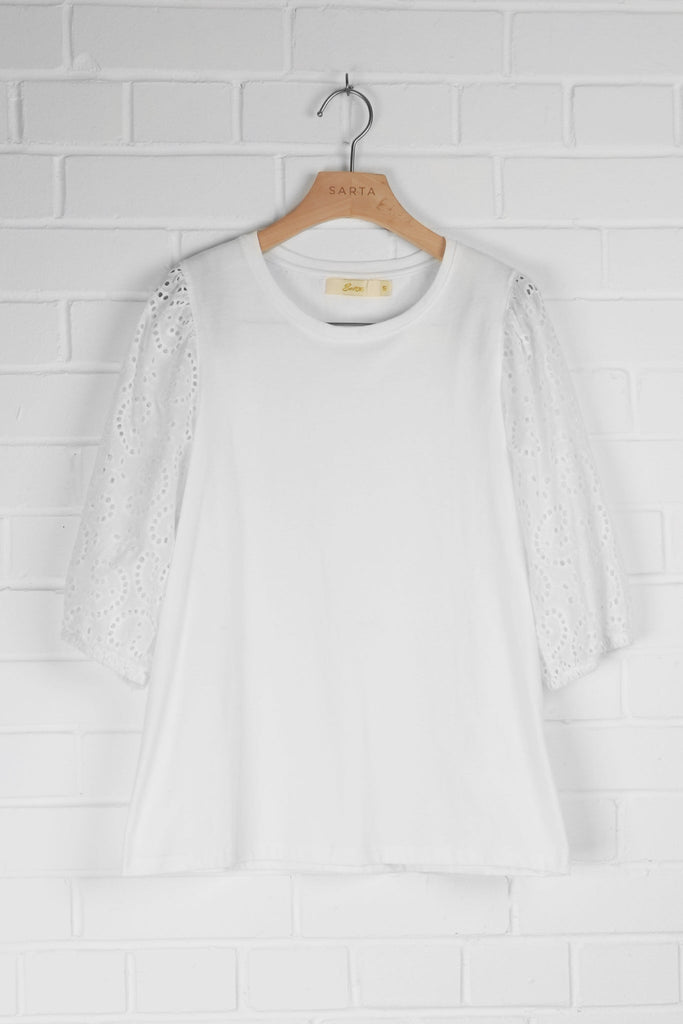 white cotton top with puff style broderie anglaise sleeves hanging on a coat hanger