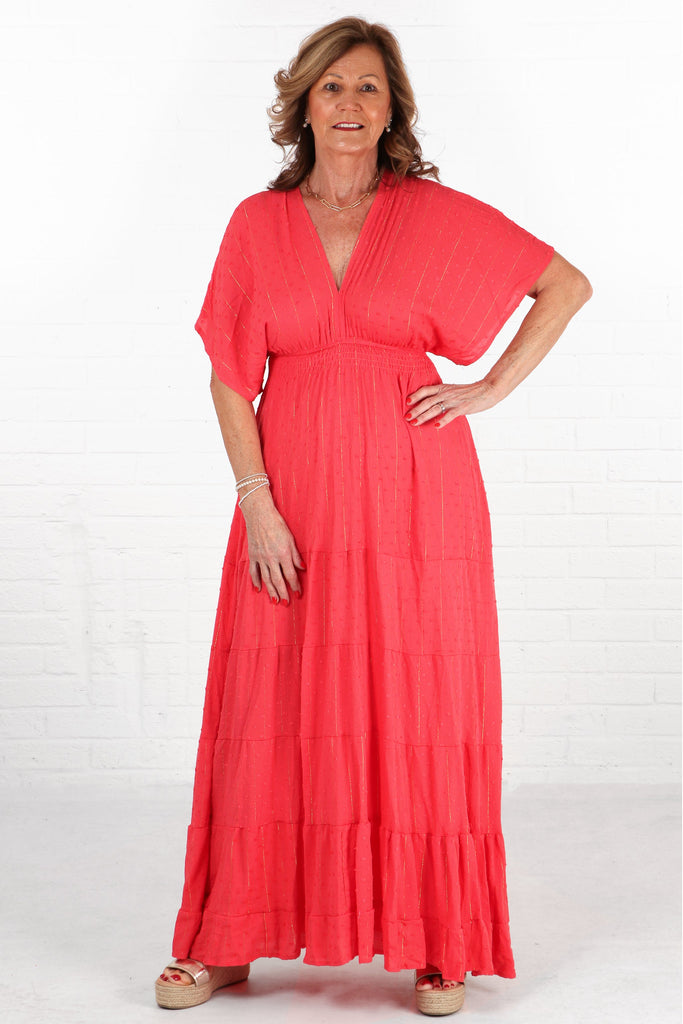 model wearing a coral coloured maxi length kaftan dress with a metallic gold foil stripe detail and dobby material