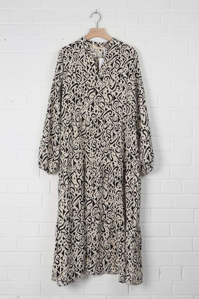 cream and black aztec pattern tiered midi dress draped on a coat hanger