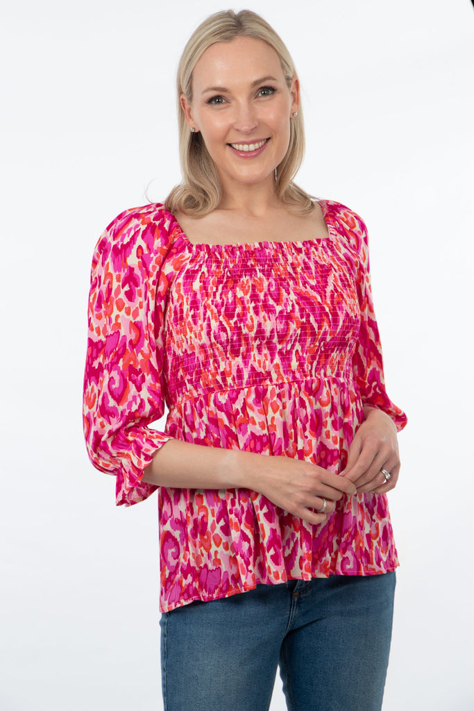 model wearing a pink abstract print 3/4 sleeve shirred bodice peplum top