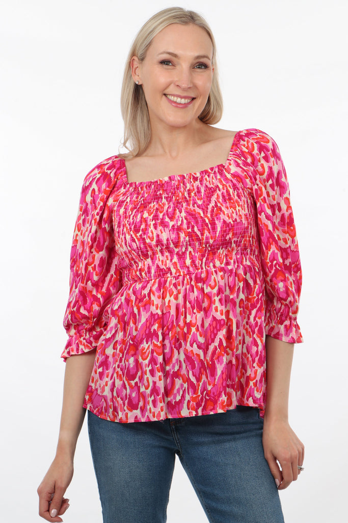 model wearing a milkmaid style peplum top with 3/4 sleeves and a shirred bodice