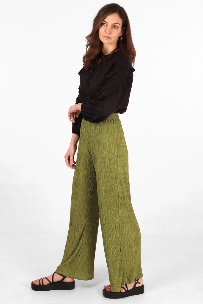 model wearing a pair of plisse material long trousers in an olive green colour