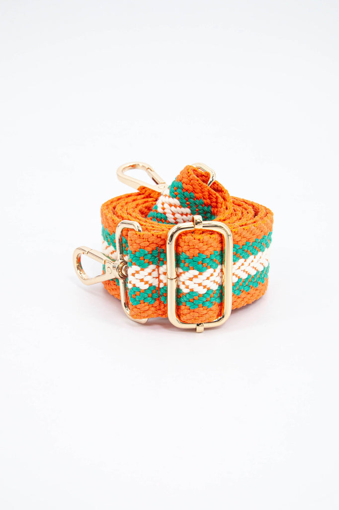 close up of the gold adjustment buckle on the orange and green contrasting chevron stripe bag strap