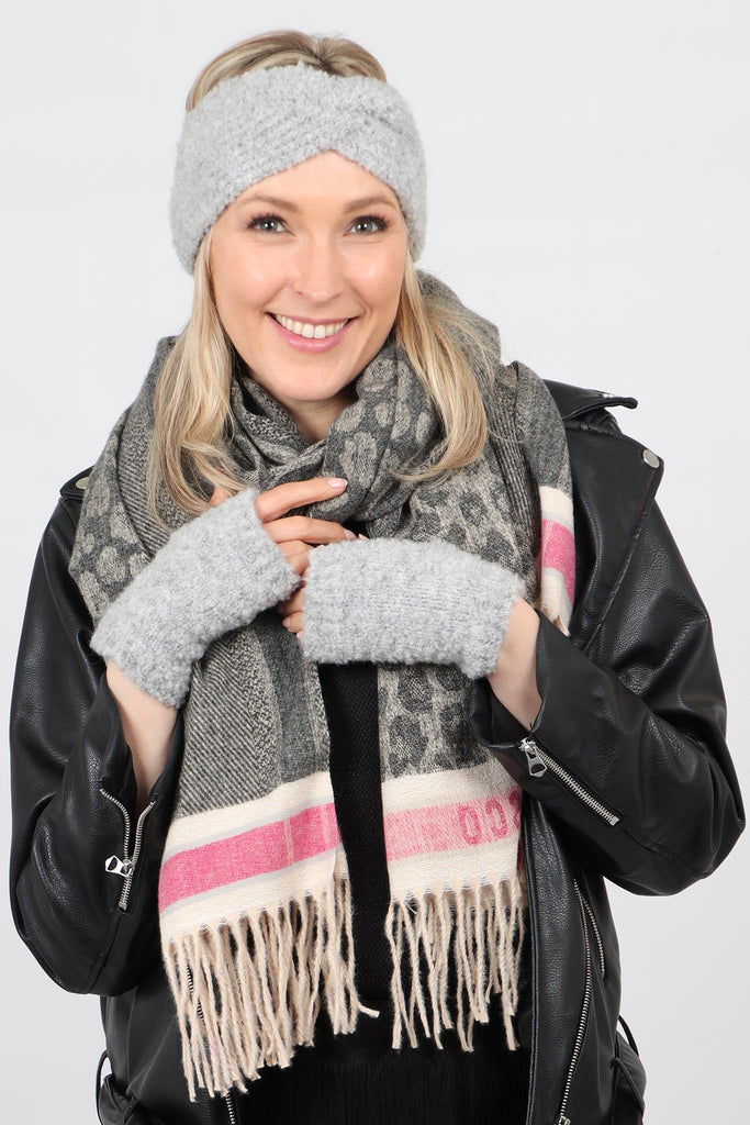 a model wearing a light grey twisted knitted head band and other winter accessories