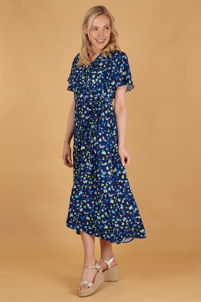 model showing a side view of the blue leopard print wrap dress showing the dipped hem design