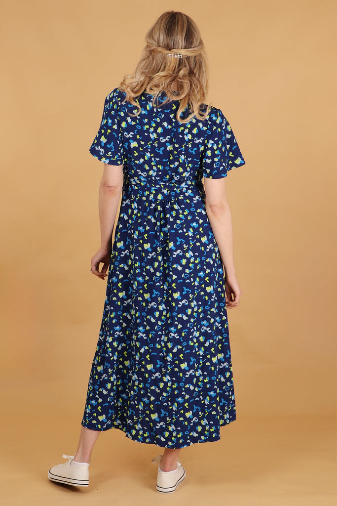 model showing the back of the blue wrap dress showing an all over pattern