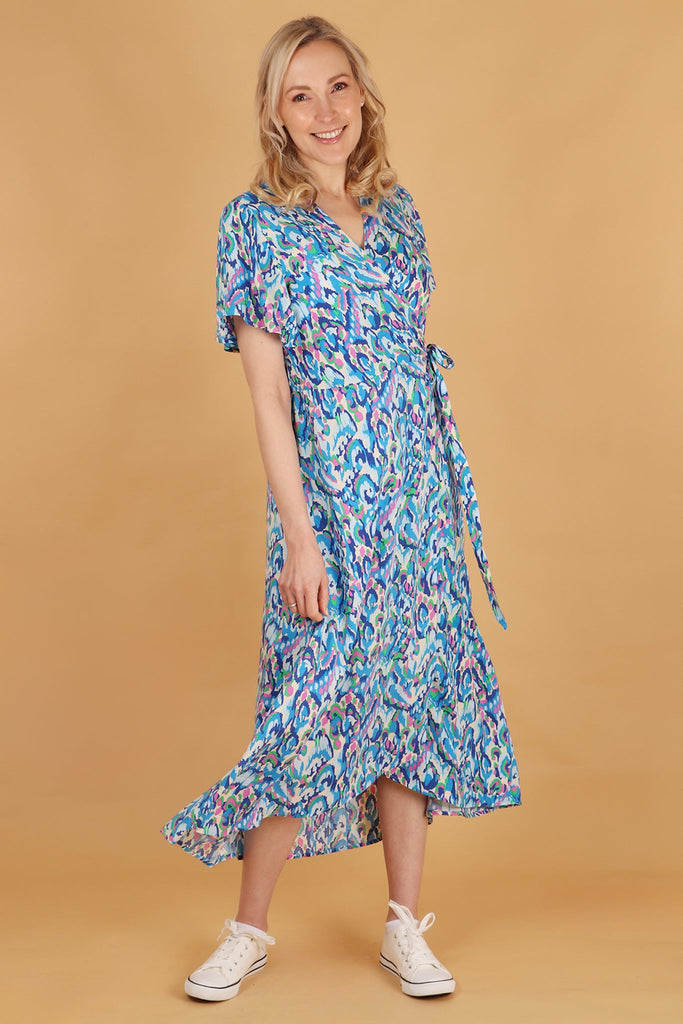 model wearing a blue midi wrap dress with an all over abstract pattern 