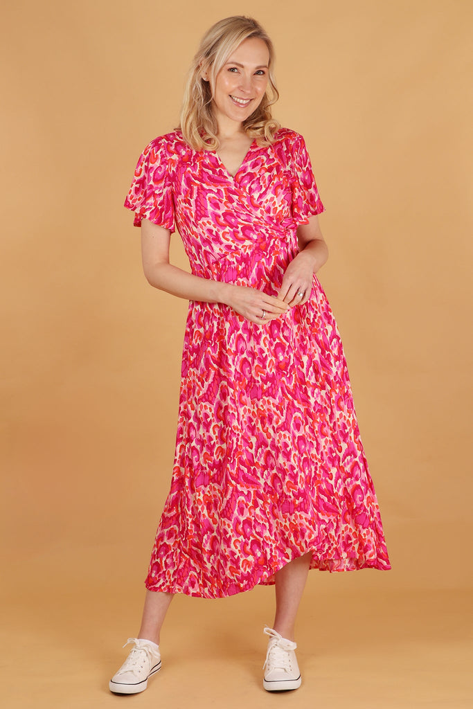 model wearing a pink midi wrap dress with an all over abstract pattern 