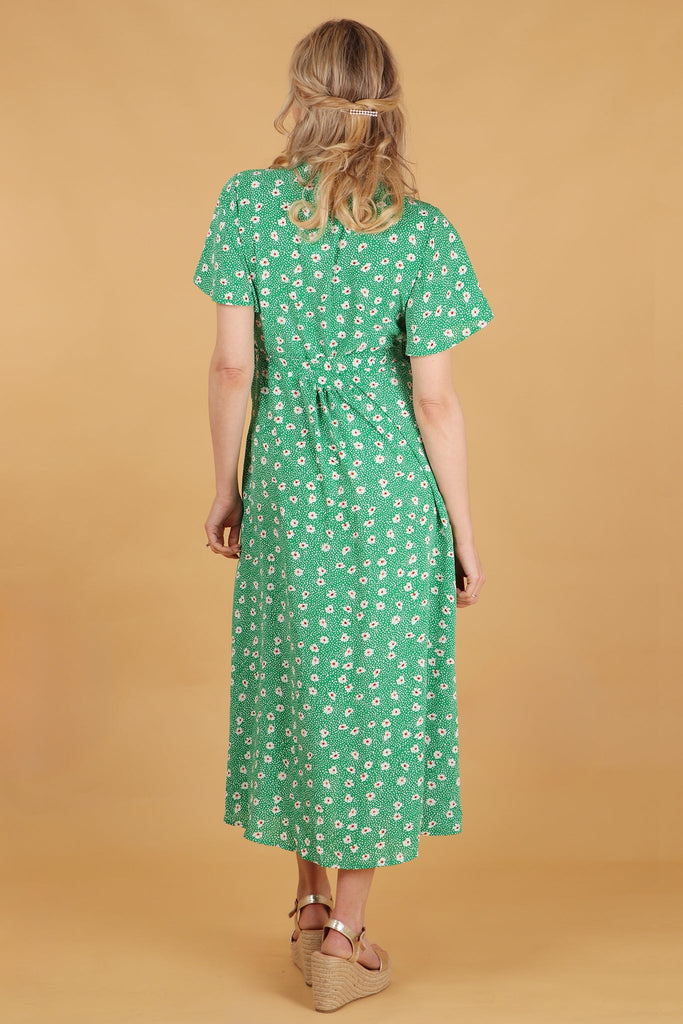 model showing the back of the green daisy print dress showing an all over pattern